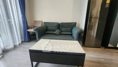 Cozy living room with modern sofa and sleek refrigerator, perfect for urban living.