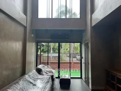 Spacious living room with high ceiling and large windows overlooking garden