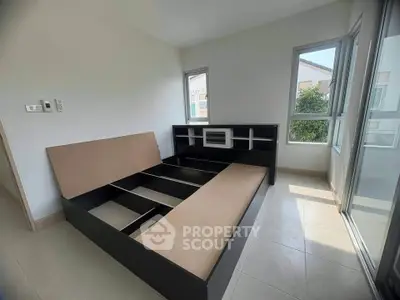 Spacious bedroom with modern bed frame and large windows offering natural light.