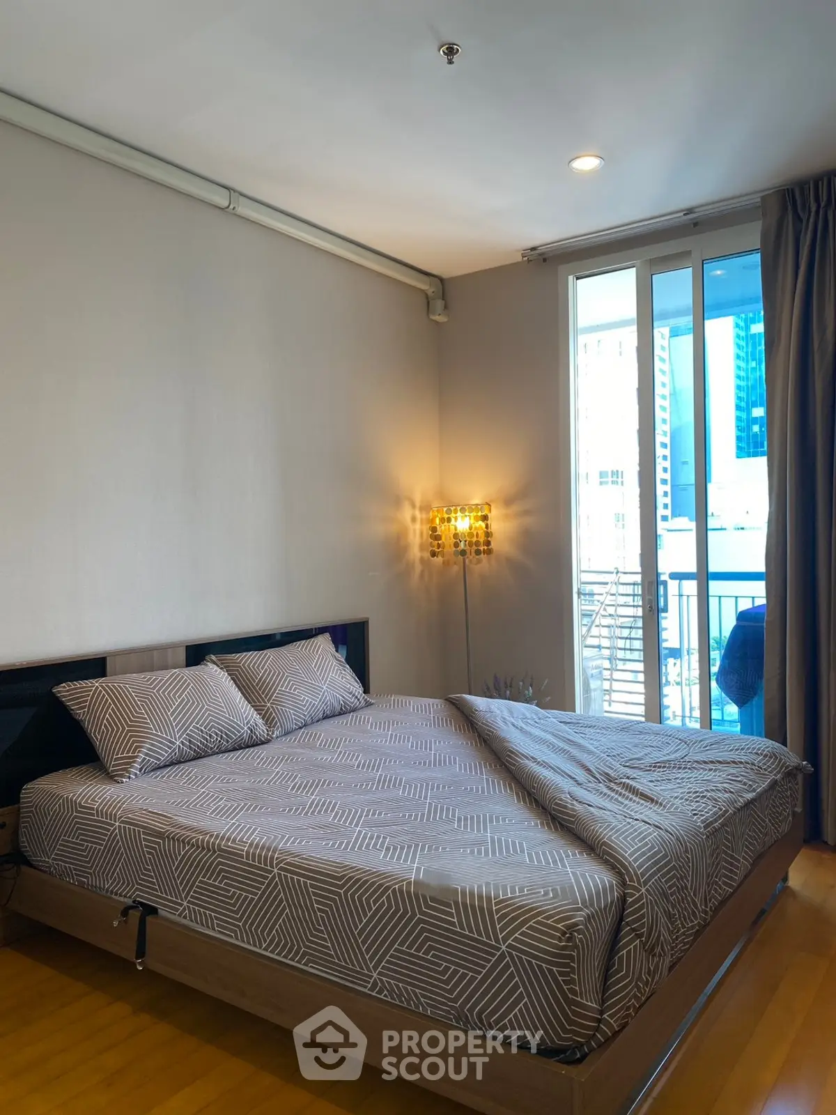 Modern bedroom with stylish decor and city view balcony access.