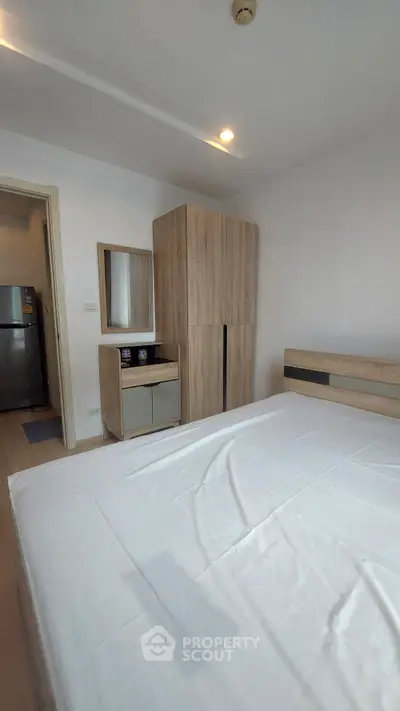 Modern bedroom with wooden furniture and white bedding in a cozy apartment.