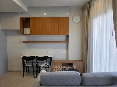 Modern living room with sleek furniture and natural light, featuring a stylish wall clock and cozy seating area.