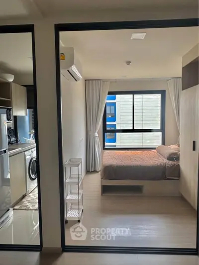 Modern apartment interior with bedroom and kitchen, featuring sleek design and natural light.