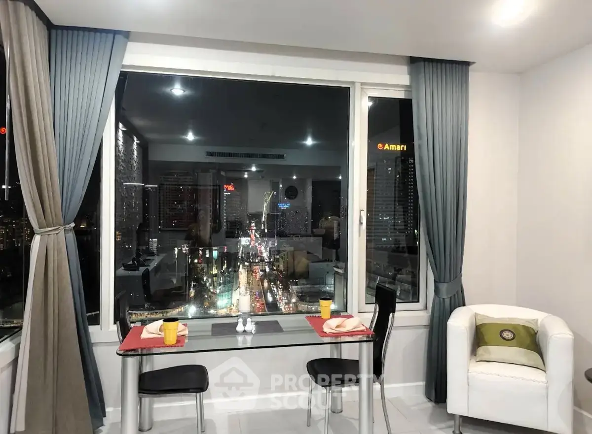 Modern living room with stunning city view through large windows, featuring elegant dining setup and cozy seating.