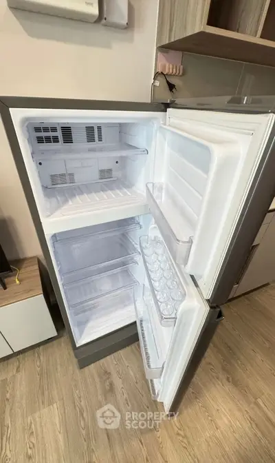 Modern kitchen with open fridge showcasing spacious interior and sleek design.