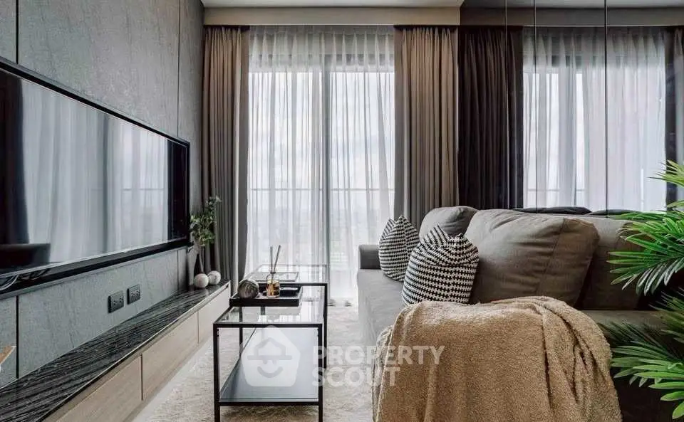Modern living room with large TV, stylish furniture, and floor-to-ceiling windows.