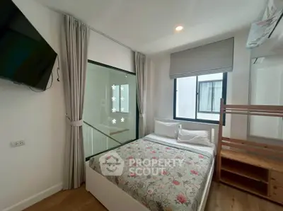 Cozy bedroom with floral bedding and modern decor, featuring a wall-mounted TV and ample natural light.