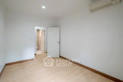 Spacious empty room with wooden flooring and air conditioning, ideal for customization.