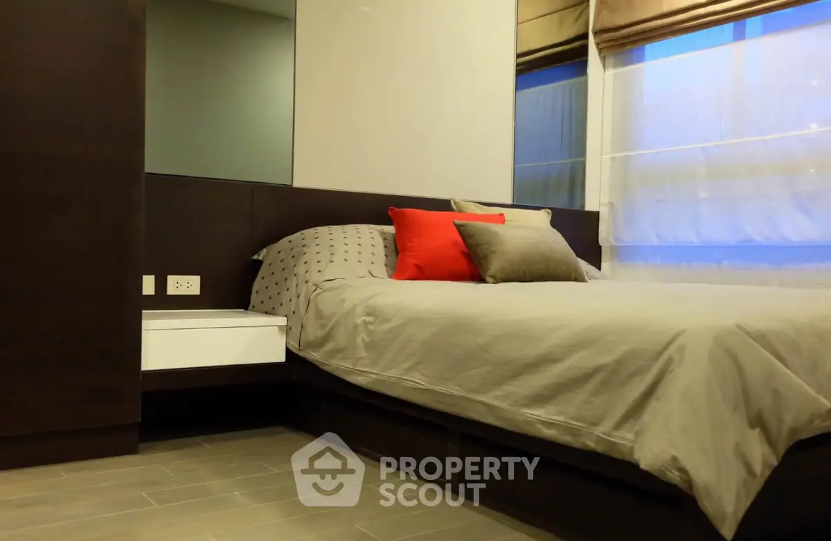 Modern bedroom with stylish decor and large window for natural light.