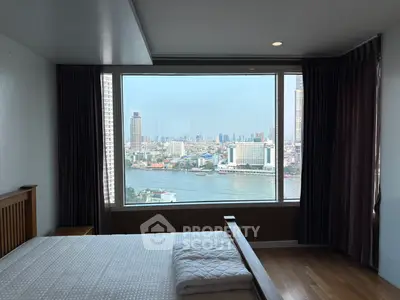 Luxurious bedroom with stunning river view and large window in modern high-rise apartment.