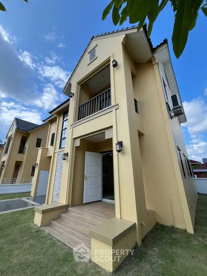 Elegant two-story house with modern architecture and lush green lawn under a clear blue sky.