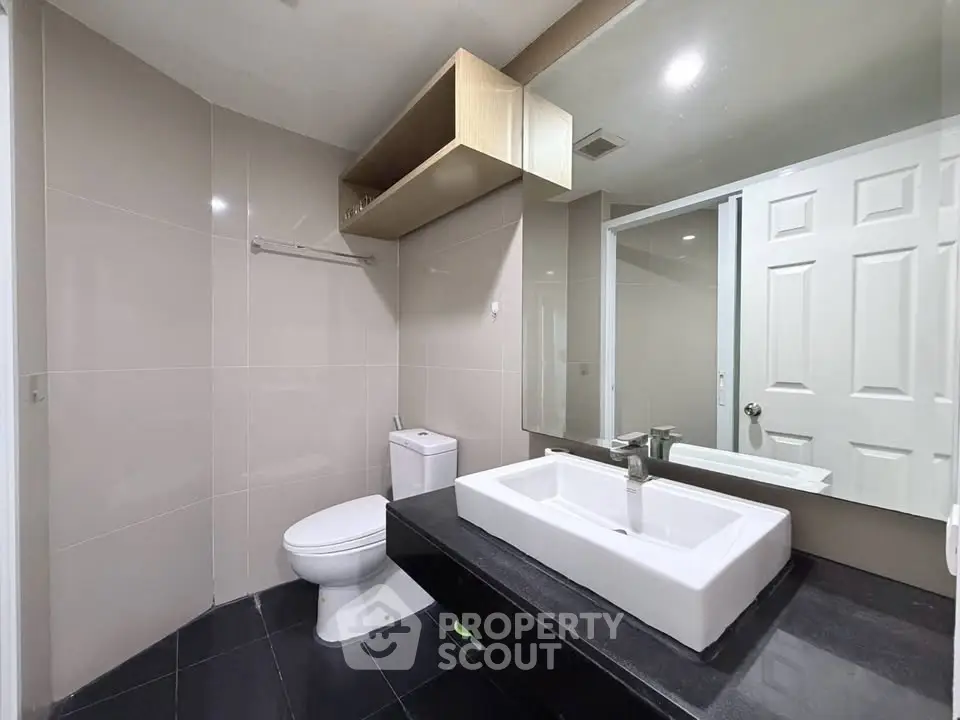 Modern bathroom with sleek fixtures and large mirror in a contemporary home.