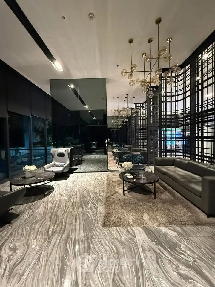 Luxurious modern lobby with elegant chandeliers and stylish seating area in upscale building.