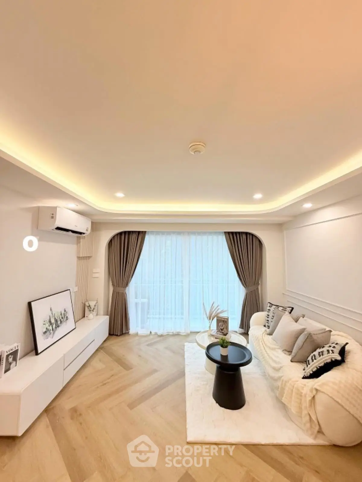 Elegant living room with modern decor and large window, featuring cozy seating and stylish lighting.