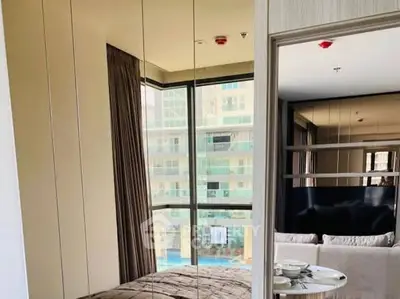 Modern bedroom with mirrored walls and large windows overlooking a pool view.