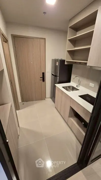 Modern compact kitchen with sleek cabinetry and stainless steel appliances in a cozy apartment.