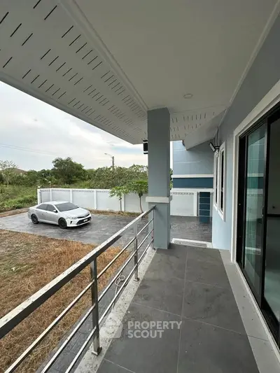 Spacious balcony with modern railing overlooking driveway and parked car, perfect for outdoor relaxation.