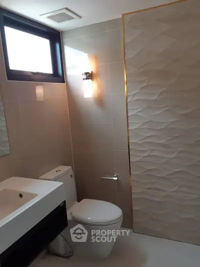 Modern bathroom with elegant tile design and natural light.