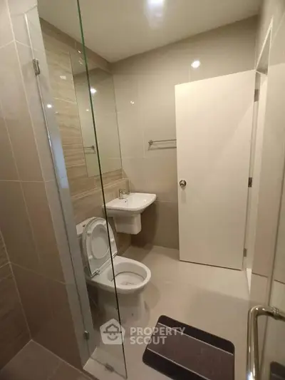 Modern bathroom with glass shower and sleek fixtures in contemporary apartment.