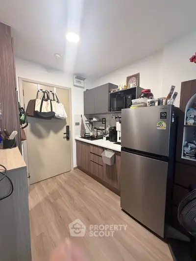 Modern compact kitchen with sleek cabinets and stainless steel fridge in cozy apartment.