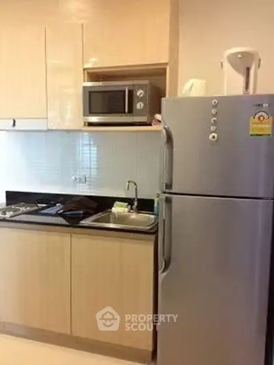 Modern kitchen with stainless steel fridge and microwave in sleek apartment.