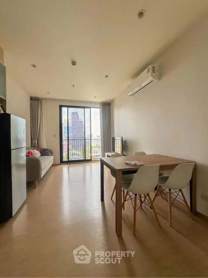 Spacious living room with modern furniture and city view balcony in a high-rise apartment.