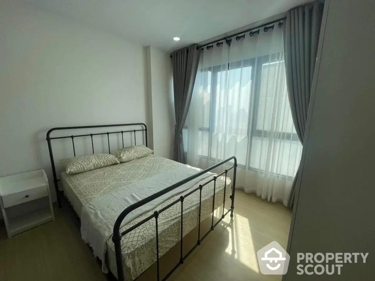 Cozy bedroom with elegant metal bed frame and floor-to-ceiling windows for natural light.