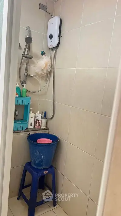 Compact bathroom with shower and water heater, ideal for efficient space use.