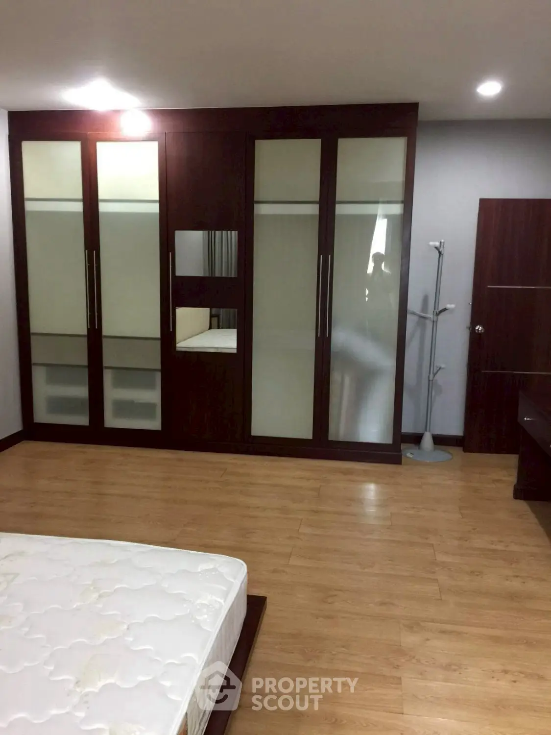 Spacious bedroom with wooden flooring and large wardrobe