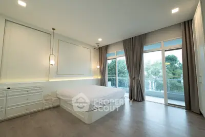 Spacious bedroom with large windows and balcony access, featuring modern decor and ample natural light.