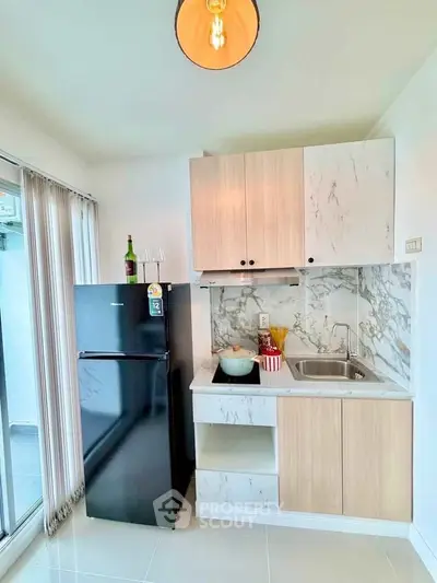 Modern kitchen with sleek black fridge and marble countertops in bright apartment