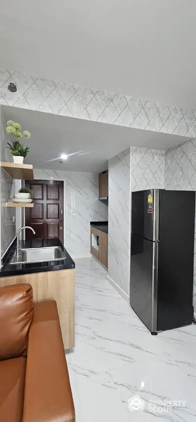 Modern kitchen with sleek black fridge and marble countertops in stylish apartment