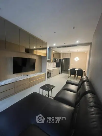 Modern living room with sleek black leather sofa and open kitchen layout