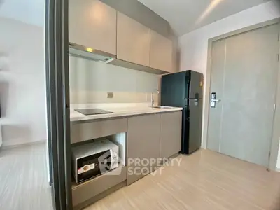 Modern compact kitchen with sleek cabinetry and appliances in a stylish apartment.