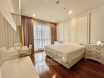 Spacious bedroom with elegant decor and large window offering natural light.