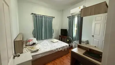 Cozy bedroom with air conditioning and natural light, featuring a comfortable bed and wooden flooring.