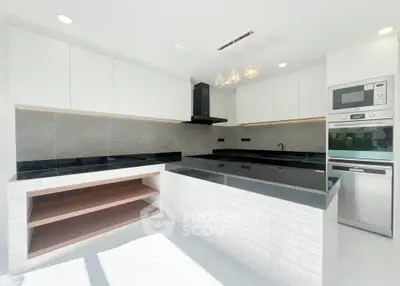 Modern kitchen with sleek black countertops and built-in appliances in a bright, minimalist design.