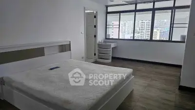 Spacious bedroom with large windows offering city views, featuring modern flooring and minimalist design.