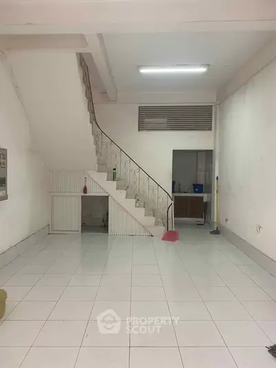 Spacious interior with tiled flooring and staircase, ideal for creative renovation.