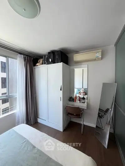 Cozy bedroom with wardrobe, vanity, and large window for natural light.