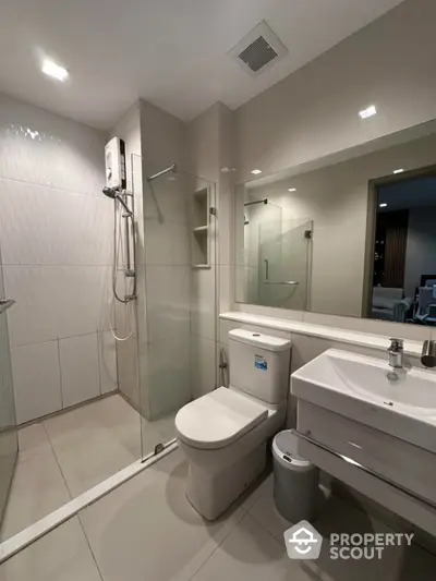 Modern bathroom with glass shower and sleek fixtures in contemporary apartment.