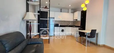 Modern open-plan living room with kitchen, featuring sleek furniture and contemporary lighting.