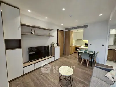 Modern living room with stylish furniture and open dining area, featuring sleek wooden flooring and contemporary decor.