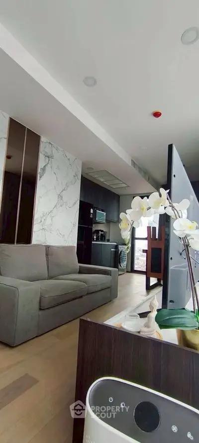 Modern living room with stylish decor and open kitchen layout, featuring sleek appliances and elegant furnishings.