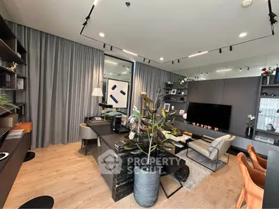 Modern living room with stylish decor and open layout, featuring a large TV and elegant furniture.