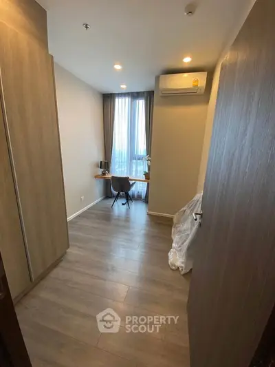 Modern study room with wooden flooring and natural light, featuring a compact desk and chair.