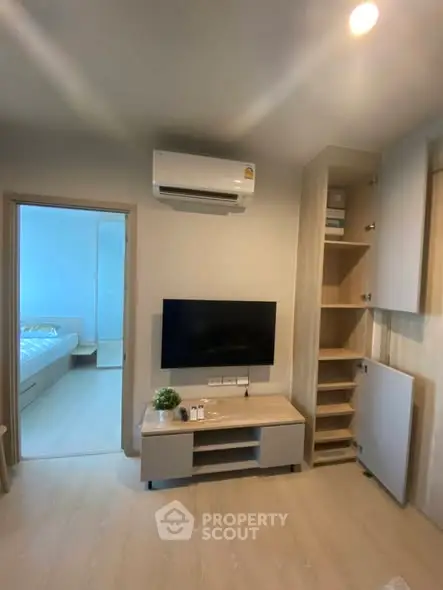 Modern living room with air conditioning and TV, leading to a bright bedroom.