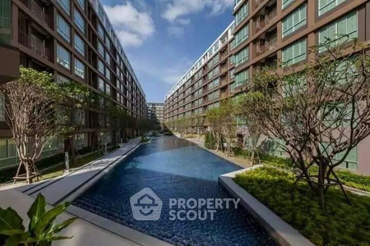 Luxurious modern apartment complex with stunning central pool and lush landscaping.