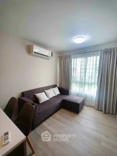 Modern living room with sleek sofa and large window in a stylish apartment.