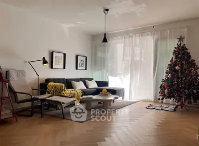 Stylish living room with Christmas tree, modern furniture, and natural light.
